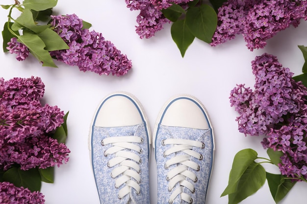 Sneakers with branches of blooming lilacs on white background Spring concept Top view Flat lay