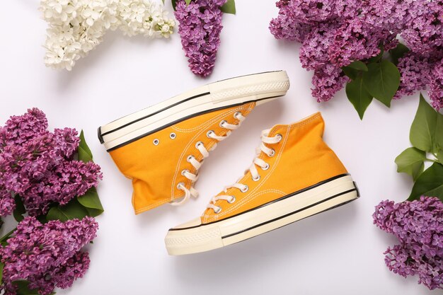 Sneakers with branches of blooming lilacs on white background Spring concept Top view Flat lay