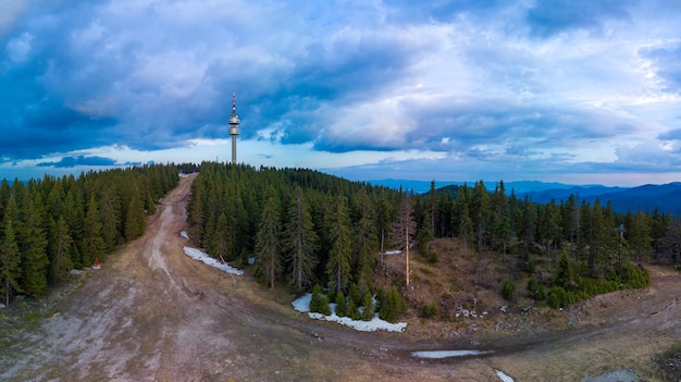 Snezhanka tower in valley of rhodope mountains and forests against clouds panorama top view