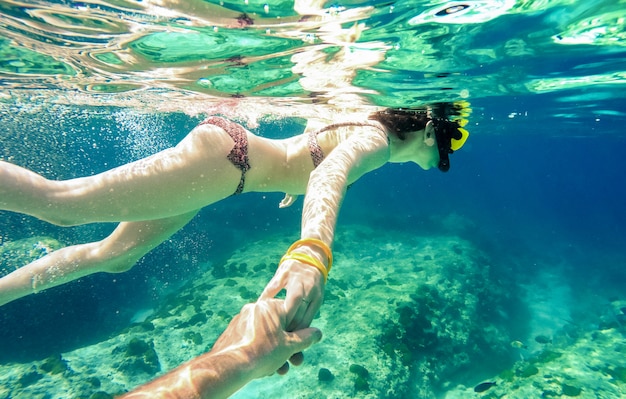 Snorkel couple swimming together in tropical sea with follow me composition