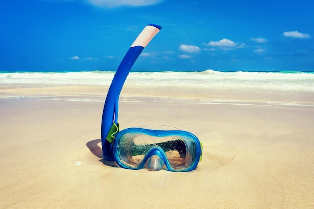 The snorkel mask on the sand with the beach background