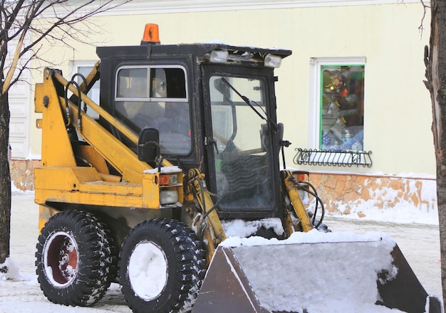 Snow bulldozer - clearing snow on the winter street, urban landscape