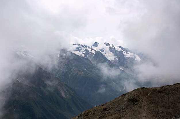 Snow capped mountain range in the clouds. Caucasus, Russia.