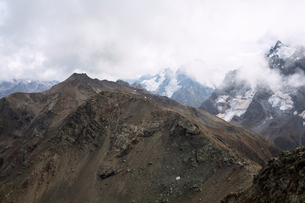 Snow capped mountain range in the clouds. Caucasus, Russia.