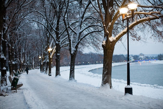 Snow-covered embankment in evening city. Beautiful winter landscape