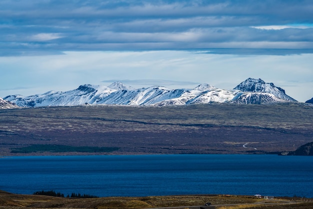 Snow covered mountain range road car and lake under the clouds