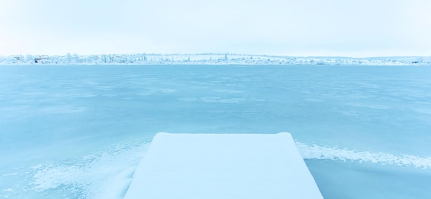 Snow-covered pier in a frozen lake. Winter landscape, cold weather. Tourism in winter. Copy space.