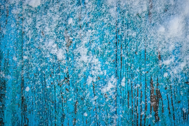 Snow-covered wooden blue table with peeling paint