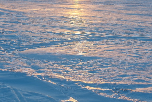 A snow crust on the frozen winter lake at sunset