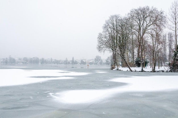 The snow falls on the bare trees and the frozen lake of Enghien-les-Bains