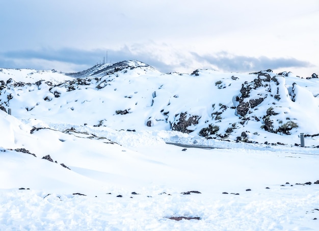 Snow field with white mountains under cloudy sky in Iceland