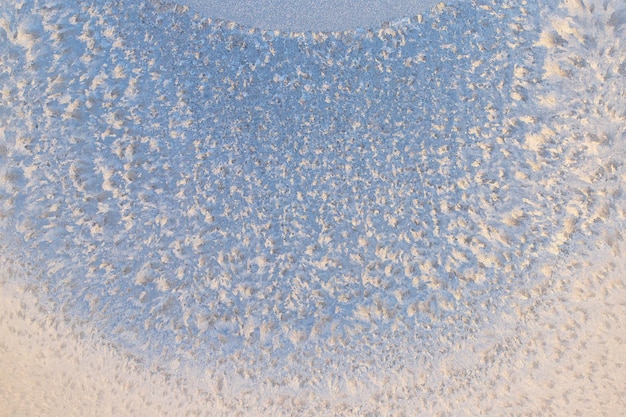 snow frost in the form of natural patterns on the window pane against the background