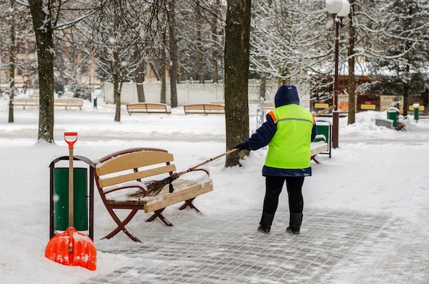 Snow storm in the city Roads and sidewalks covered with snow Worker shovel clears snow Bad winter weather Street cleaning after snowstorm