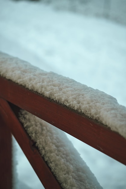 Snow on the wooden terrace during winter Snowcovered handrail made of wood