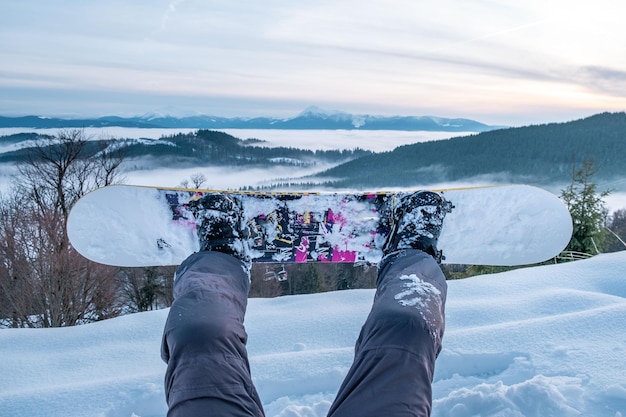 Snowboarder enjoying the view of sunset above the mountains