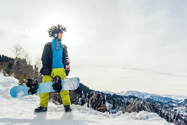 Snowboarder freerider in the mountains is preparing to descend on the background of snowy mountains