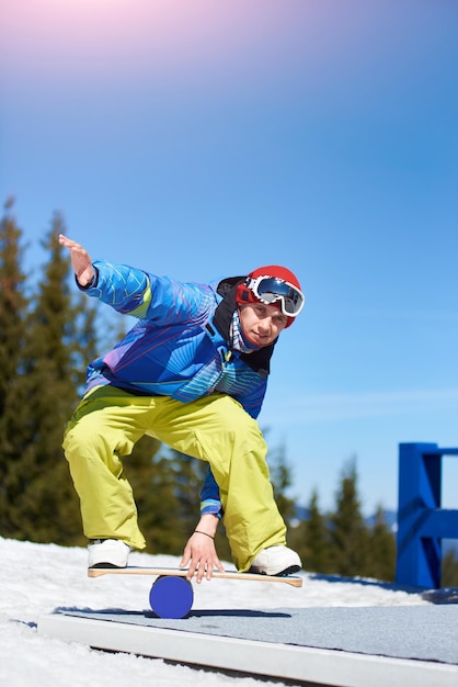 Snowboarder keeps balance on the trainer board with roller at mountains