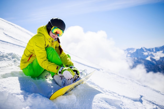 Snowboarder sitting with mountain chain in the background