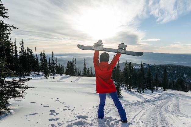 Snowboarder with a snowboard in her hands against the backdrop of a beautiful landscape