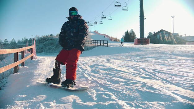 Snowboarding outdoors concept  an injured man with prosthetic leg skating down the mountain