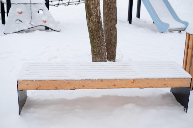 Snowcovered empty bench on the street on the playground