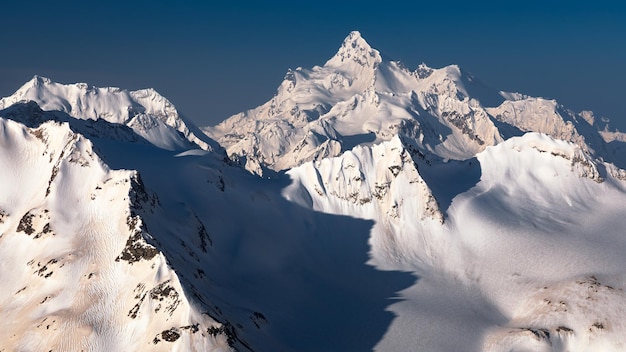 Snowcovered high mountain peaks with deep shadows against clear blue sky Caucasus Russia