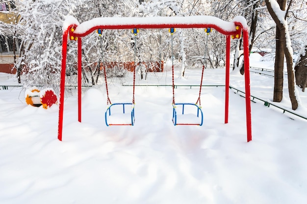 Snowcovered public kids swing in winter