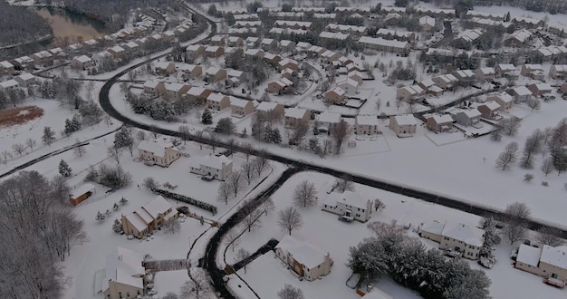 Snowfall over small town residential with snow covered roofs houses in usa countryside winter aerial