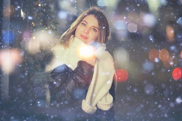 Photo snowfall woman city christmas outside, city portrait in snowfall, young model posing in festive look