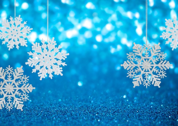 Snowflake hang on Winter holidays blue background with copy space