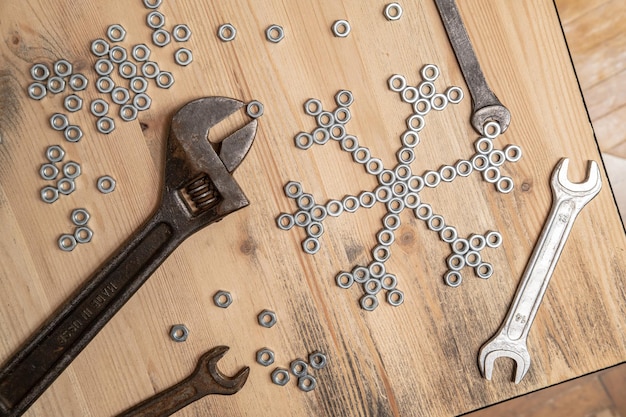 Snowflake made of metal nuts and wrenches on a wooden table Winter symbol New Year and