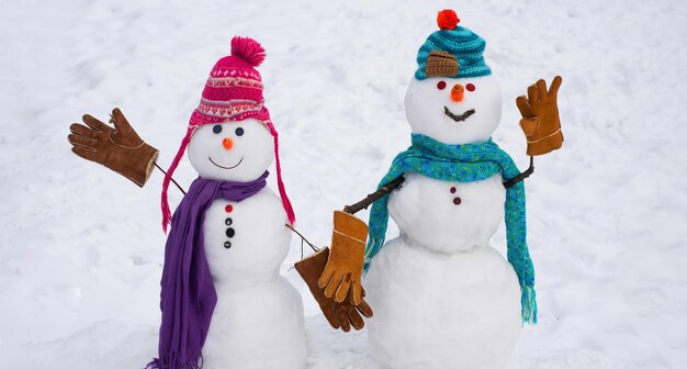 Snowman in hat and scarf on snowy field merry christmas and happy new year greeting card with copy s