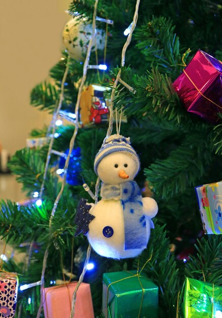 Snowman Ornament with Many Square Shaped Gift Boxes Hanging on the Sparkling Christmas Tree