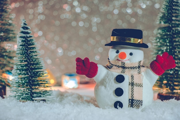 Snowman stand in pile of snow at silent night with Christmas tree and ornament