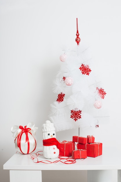 Snowmen decoration by the Christmas tree with red gift box