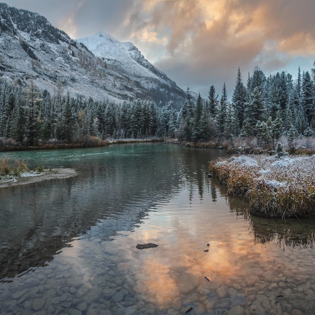 Snowy autumn landscape mountain river on a gloomy evening reflection