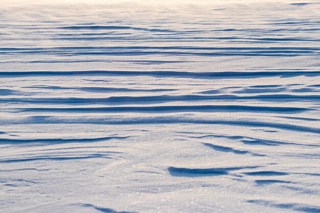 Snowy background, snow-covered surface of the earth after a blizzard in the morning in the sunlight with distinct layers of snow