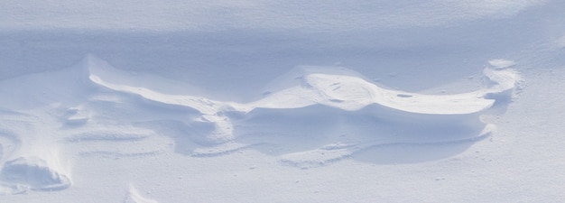 Snowy background, snow-covered surface of the earth after a blizzard in the morning in the sunlight with distinct layers of snow