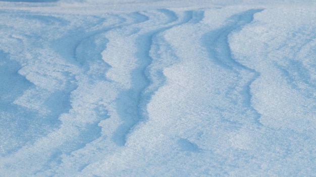 Snowy background, snow-covered surface of the earth after a blizzard in the morning in the sunlight with distinct layers of snow