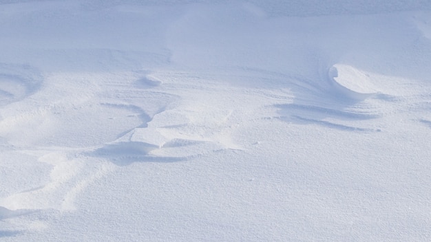 Snowy background, snow-covered surface of the earth after a blizzard in the morning in the sunlight with distinct layers of snow