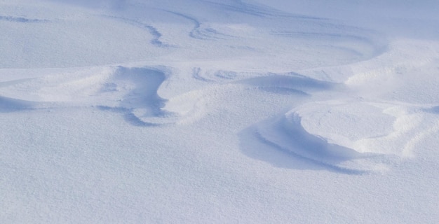 Snowy background, snow-covered surface of the earth after a blizzard in the morning in the sunlight with distinct layers of snow