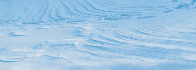 Snowy background, snow-covered surface of the earth after a blizzard in the morning in the sunlight with distinct layers of snow