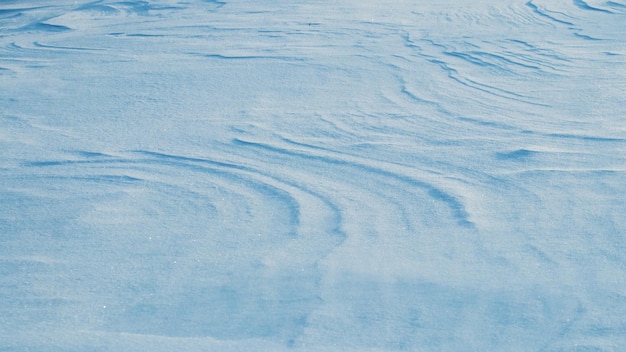 Snowy background, snow-covered surface of the earth after a blizzard in the morning in the sunlight with distinct layers of snow