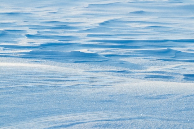 Snowy background, snow-covered surface of the earth after a blizzard in the morning in the sunlight with distinct layers of snow