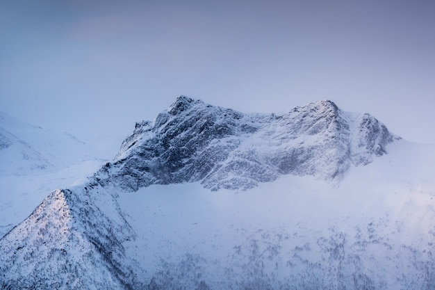 Snowy mountain peak with light in foggy