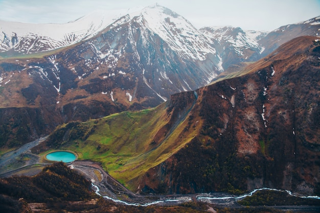 Snowy mountains and blue lake in green valley