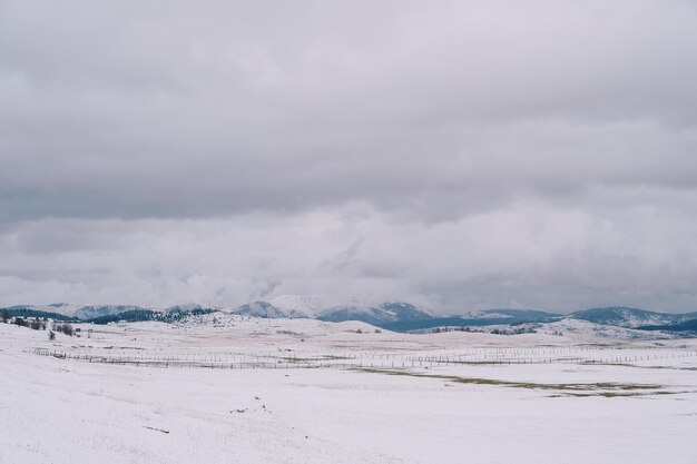 Snowy pastures in a mountain valley with wooden fences