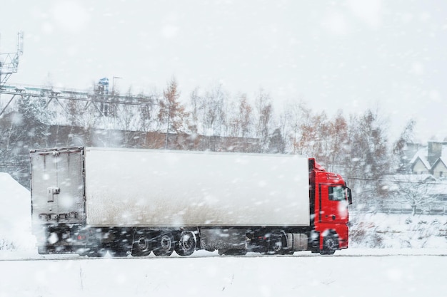 Photo snowy road trip for a semitruck the photo captures a big industrial truck transporting cargo on a winter road with a lot of snow and ice the road is surrounded by white hills and trees