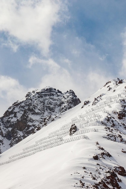 Snowy rocky mountains with avalanche protection barriers vertical copy space