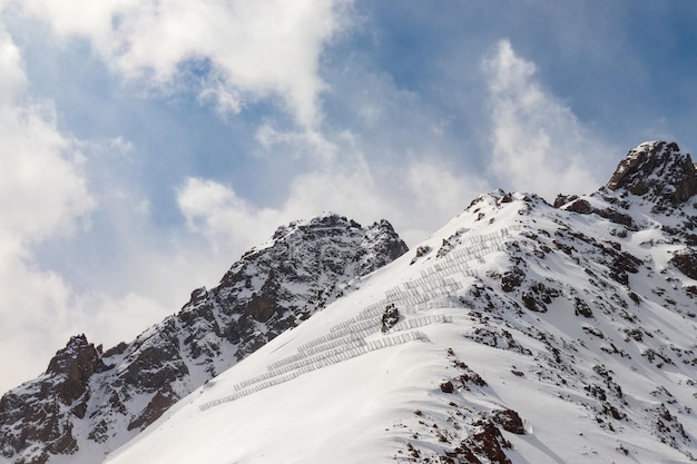 Snowy rocky mountains with avalanche protection barriers